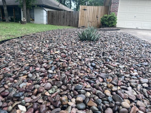 Finished river rock landscaping bed along a driveway